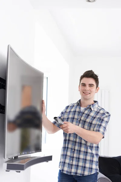 Hombre joven con nueva pantalla curvada de televisión en casa —  Fotos de Stock