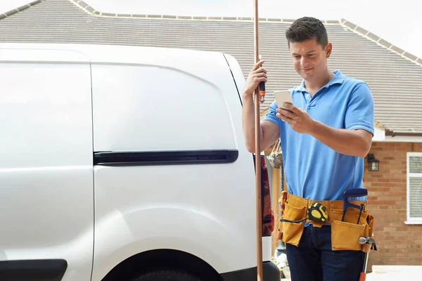 Fontanero con furgoneta usando teléfono móvil fuera de casa — Foto de Stock