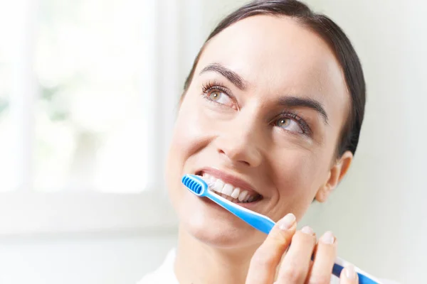 Kvinna som borstar tänderna med tandborsten i badrum — Stockfoto