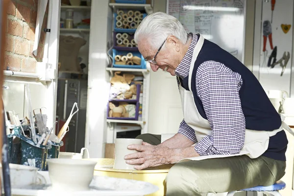 Старший человек, работающий на гончарном круге в студии — стоковое фото