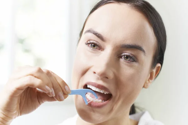 Mujer joven con dientes de hilo dental en el baño — Foto de Stock