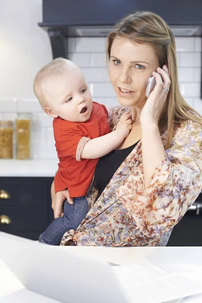 Upptagen mamma med bebis att hantera stressig dag hemma — Stockfoto