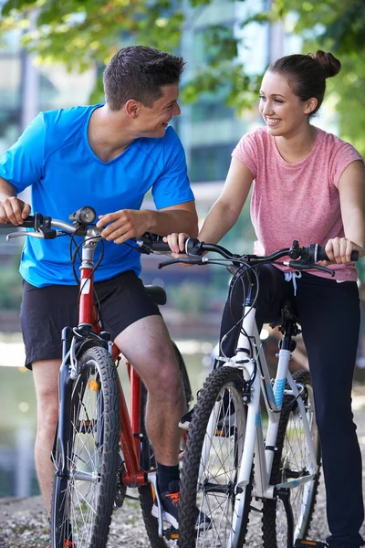 Young Couple Cycling Next To River In Urban Setting — Stock Photo, Image