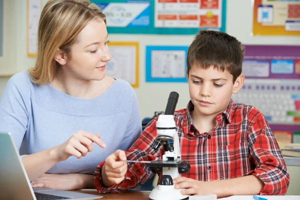 老师与男学生在科学课中使用显微镜 — 图库照片