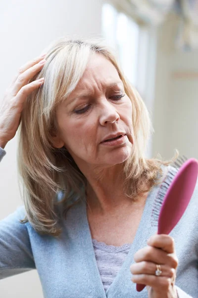 Mujer madura con cepillo Corncerned sobre la pérdida del cabello —  Fotos de Stock