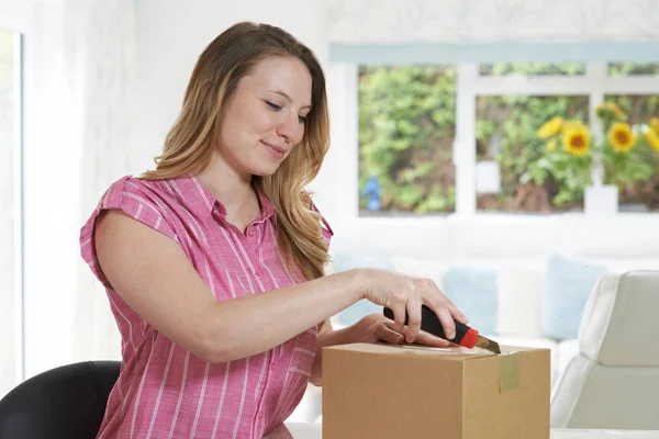 Frau öffnet Paket zu Hause mit Messer — Stockfoto