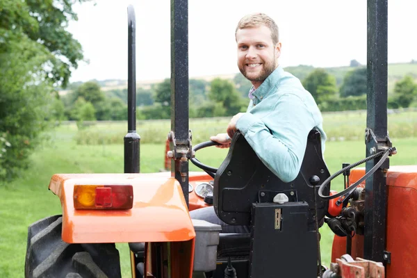 Портрет фермера сидящего на тракторе в поле — стоковое фото