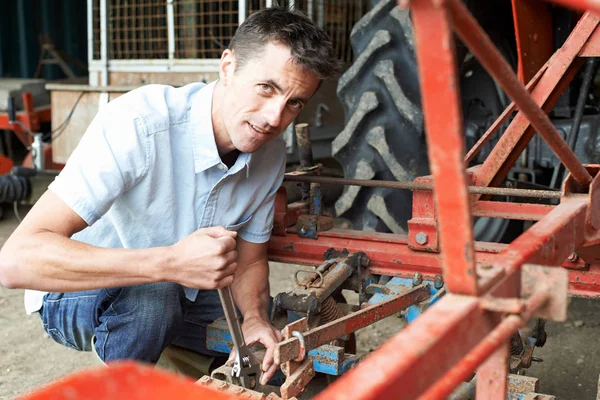 Landwirt arbeitet in Scheune an landwirtschaftlichem Gerät — Stockfoto