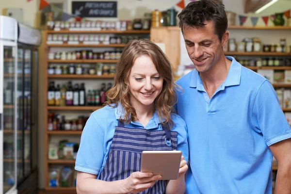 Мужчины и женщины в магазине деликатесов с использованием цифровой таблички — стоковое фото