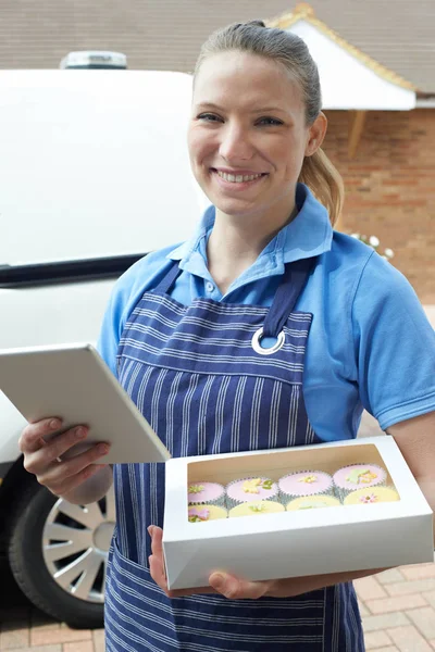 Bäckerin mit digitalem Tablet liefert Cupcake nach Hause — Stockfoto