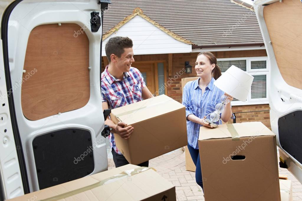 Young Couple Moving In To New Home  Unloading Removal Van