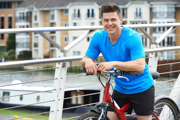 Joven ciclismo junto al río en el entorno urbano — Foto de Stock