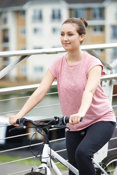 Молода жінка їде на велосипеді біля річки в міських умовах — стокове фото