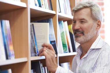 Olgun adam kitapçıda bir kitap seçimi