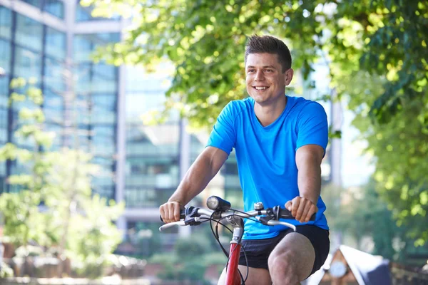 Young Man Cycling Next To River In Urban Setting — Stock Photo, Image