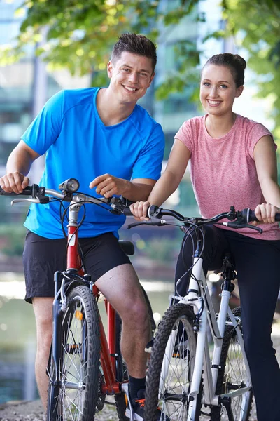 Портрет молодой пары на велосипеде рядом с рекой в городской обстановке — стоковое фото