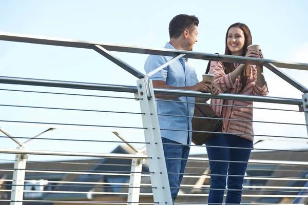 Giovane coppia parlando sul ponte in ambiente urbano tenendo take away — Foto Stock