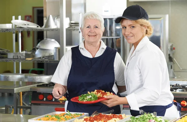 Portrait Of Two Dinner Ladies In School Cafeteria — Stock Photo, Image