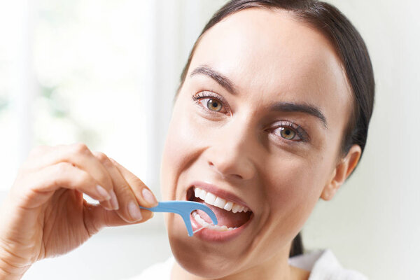 Молодая женщина зубной нитью в ванной комнате
