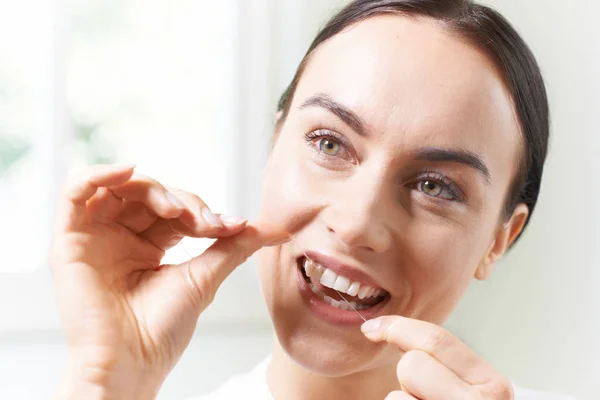 Mladá žena, flossing zuby v koupelně — Stock fotografie