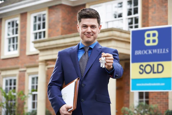 Mannelijke Realtor permanent buiten residentieel onroerend goed bedrijf sleutels — Stockfoto