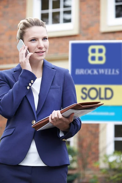Femmina agente immobiliare al telefono fuori di immobili residenziali in vendita — Foto Stock