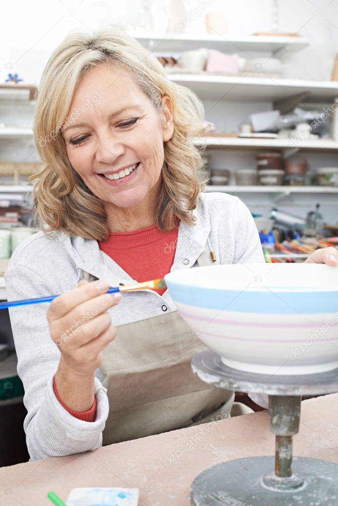 Mature Woman Decorating Bowl In Pottery Class