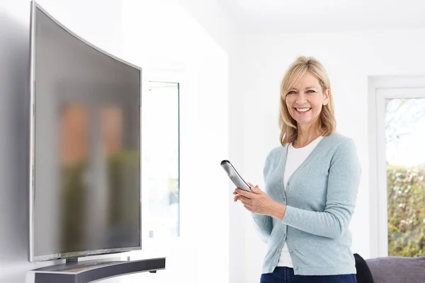 Érett nő, az új görbe képernyő televízió otthon — Stock Fotó