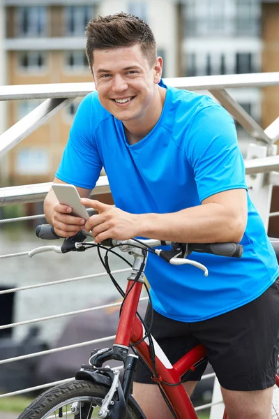 Joven usando el teléfono móvil mientras está fuera en el paseo en bicicleta en Urban S — Foto de Stock