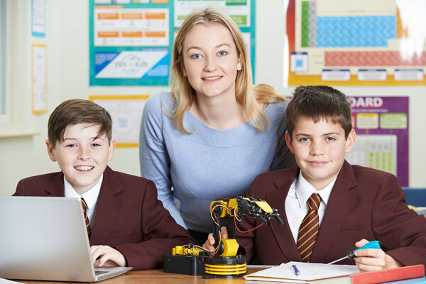 Portrait Of Teacher With Pupils In Science Lesson Studying Robot