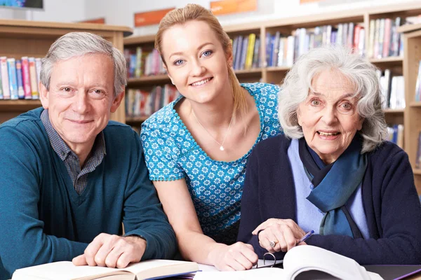 Portrait d'étudiants matures travaillant avec le professeur à la bibliothèque — Photo