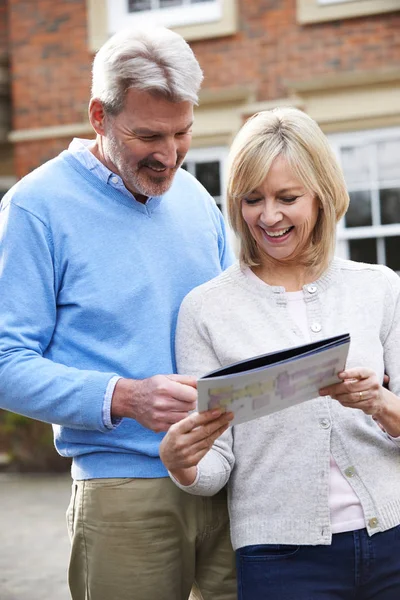 Oudere paar permanent buiten huis kijken naar bezitsdetails — Stockfoto