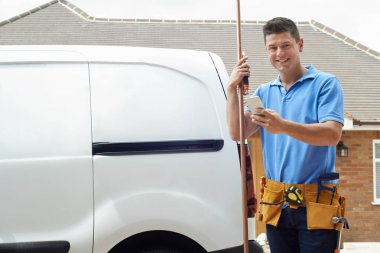 Portrait Of Plumber With Van Texting On Mobile Phone Outside Hou clipart