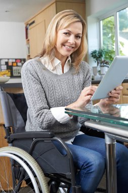 Engelli kadın evde dijital Tablet kullanarak tekerlekli sandalyede