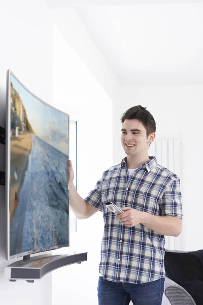 Fiatal férfi új hajlított képernyős televízió otthon — Stock Fotó