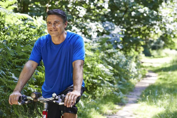 Hombre maduro ciclismo a lo largo del camino en el campo — Foto de Stock