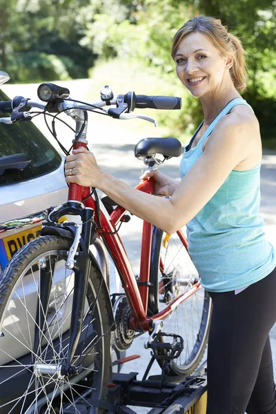 Ciclista femenina madura tomando bicicleta de montaña de rack en el coche — Foto de Stock