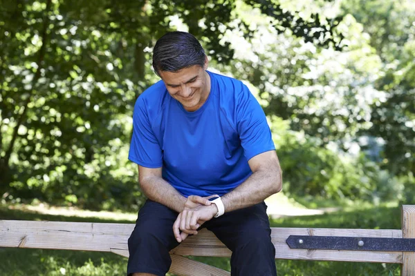 Mature Man Looking At Activity Tracker Whilst Exercising In Coun — Stock Photo, Image