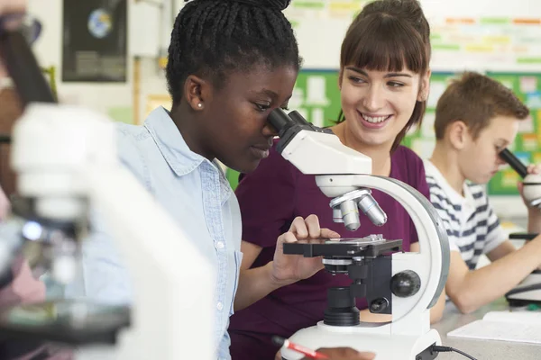 Grupo de alunos com professor usando microscópios na aula de ciências — Fotografia de Stock