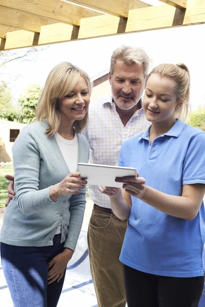 Pareja madura discutiendo plan con jardinero del paisaje usando Digi — Foto de Stock