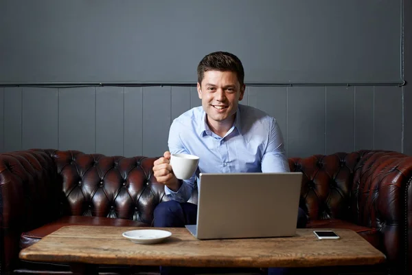 Podnikatel, pití kávy, zároveň pracovat na notebooku v Internetu — Stock fotografie