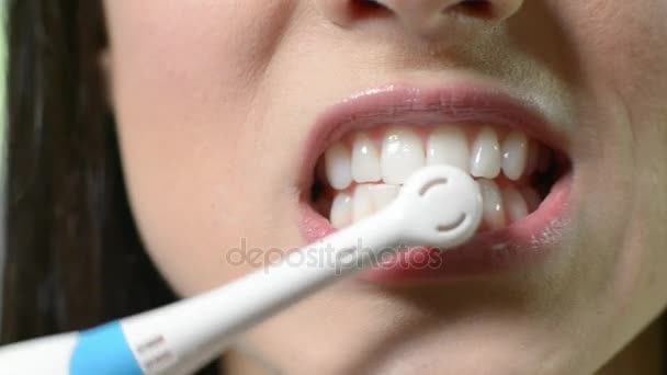 Detailní záběr ženy čištění zubů s elektrický kartáček na zuby