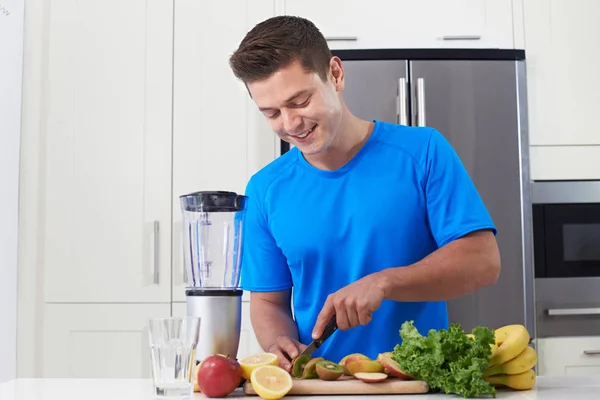 Atleta masculino fazendo suco ou smoothie na cozinha — Fotografia de Stock