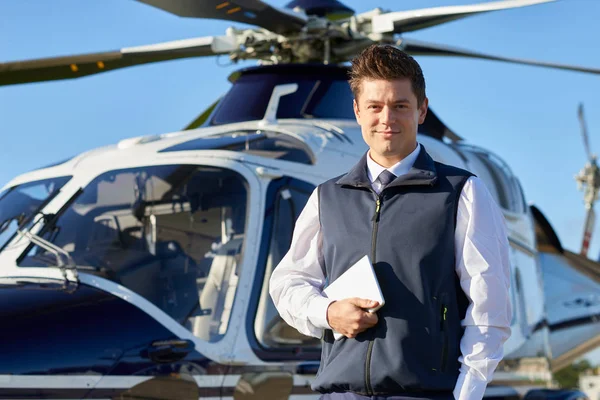 Portrét pilota stojící před vrtulník s digitálním tabletu — Stock fotografie
