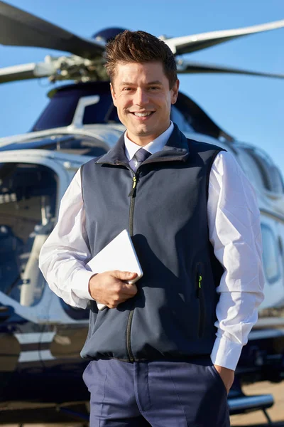Portrét mužské pilotní stojící před vrtulník s digitálním tabletu — Stock fotografie
