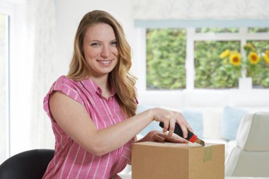 Evde paketi açmak için bıçak kullanan kadın portresi