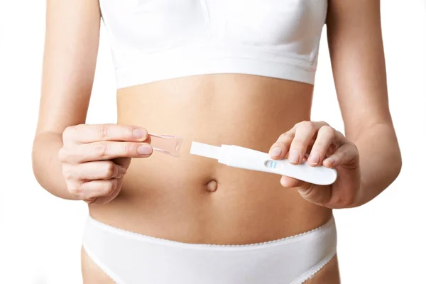 Detailní záběr z žena v prádle drží domácí pozitivní těhotenství T — Stock fotografie