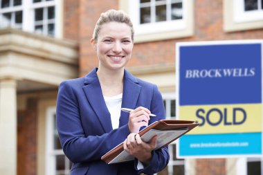 Kadın emlakçı dış konut emlak ayakta portresi