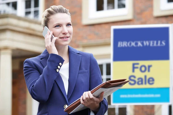 Vrouwelijke makelaar op telefoon buiten residentieel onroerend goed te koop — Stockfoto