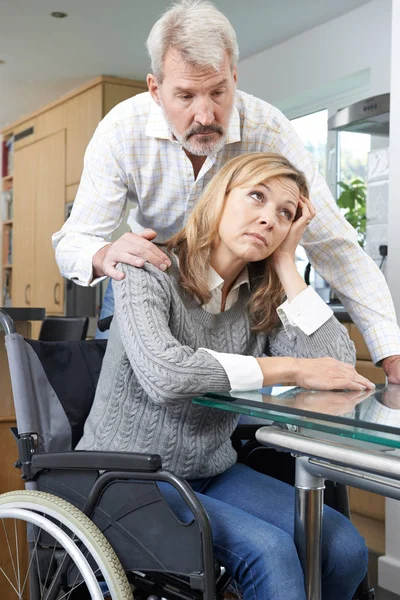 Uomo confortante donna depressa in sedia a rotelle a casa — Foto Stock